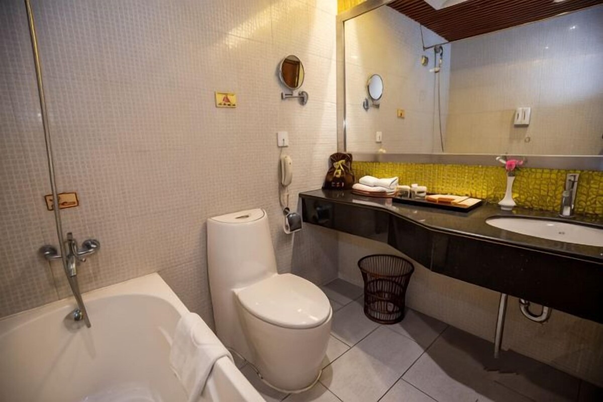 A bathroom with a bathtub, toilet, sink, and mirror.
