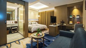 Une chambre d’hôtel avec un lit, un bureau, une chaise, une petite table avec des fruits et un téléviseur.
