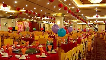 Een feestzaal met ronde tafels, ingericht voor een formeel evenement, versierd met ballonnen en tafelschikking.