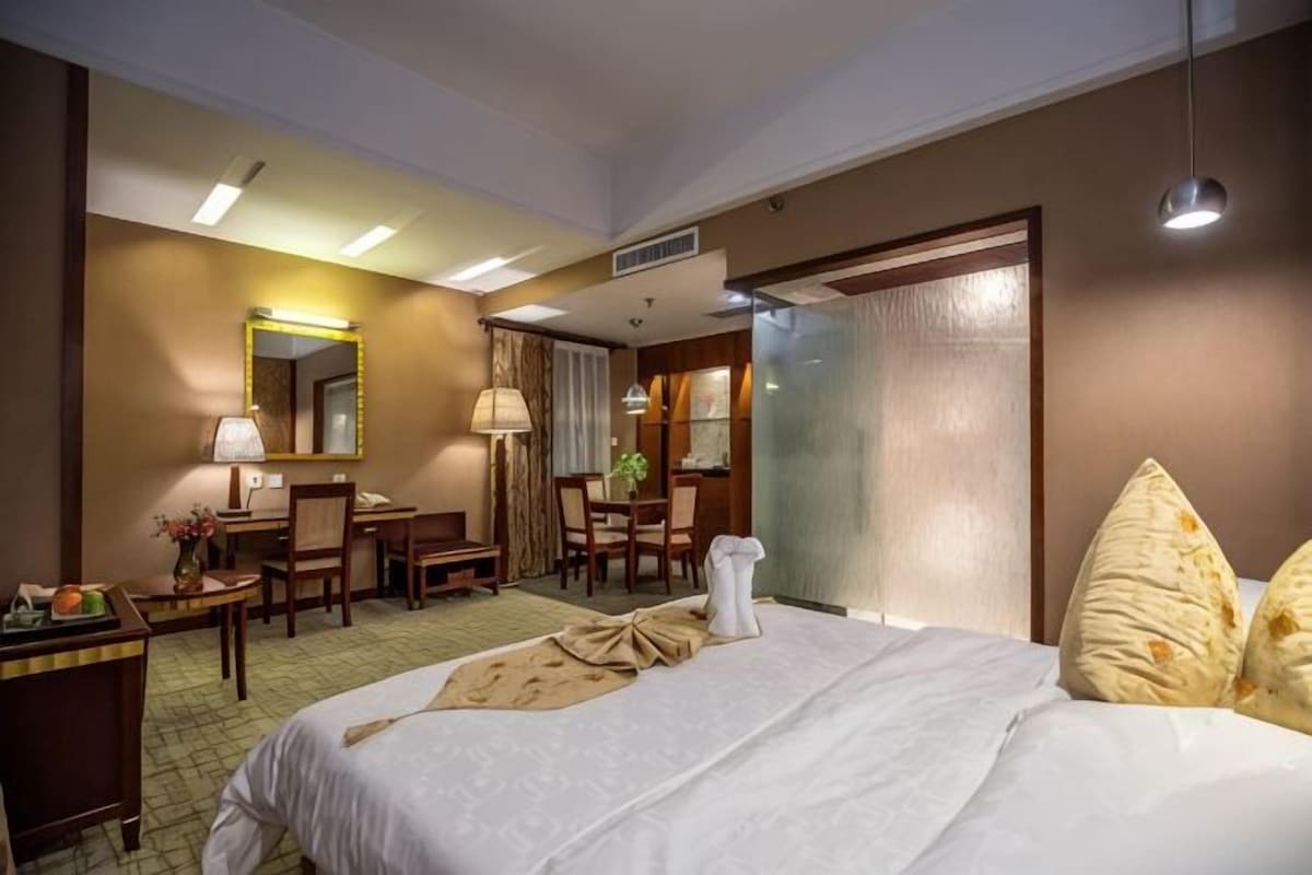 Una habitación de hotel con cama, escritorio, sillas, espejo y ventana.