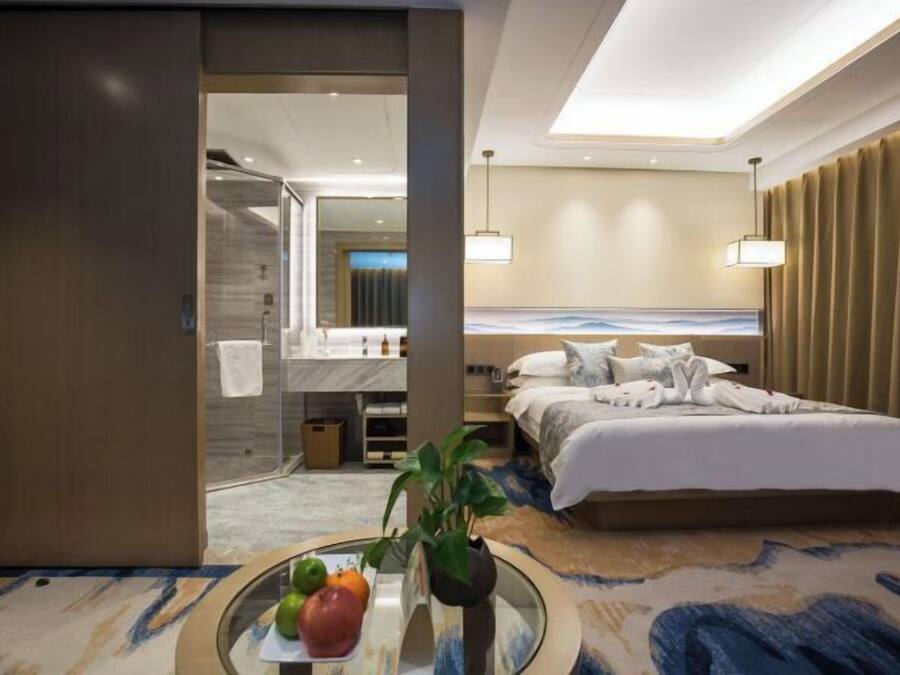 Une chambre d’hôtel moderne dotée d’un grand lit, d’une salle de bain avec douche et d’un coin repas avec une table et des chaises.
