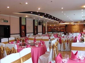 A banquet hall with round tables, white and pink tablecloths, and gold sashes. - Golden Spring Hotel (Kunming)