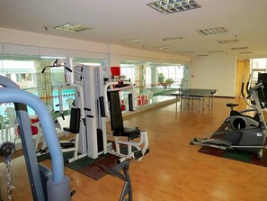 Un gimnasio con máquinas de cardio, equipo de entrenamiento con pesas y un amplio muro de espejos.