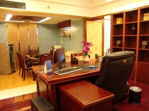 Una oficina de hotel con escritorio, computadora, silla y estantería.