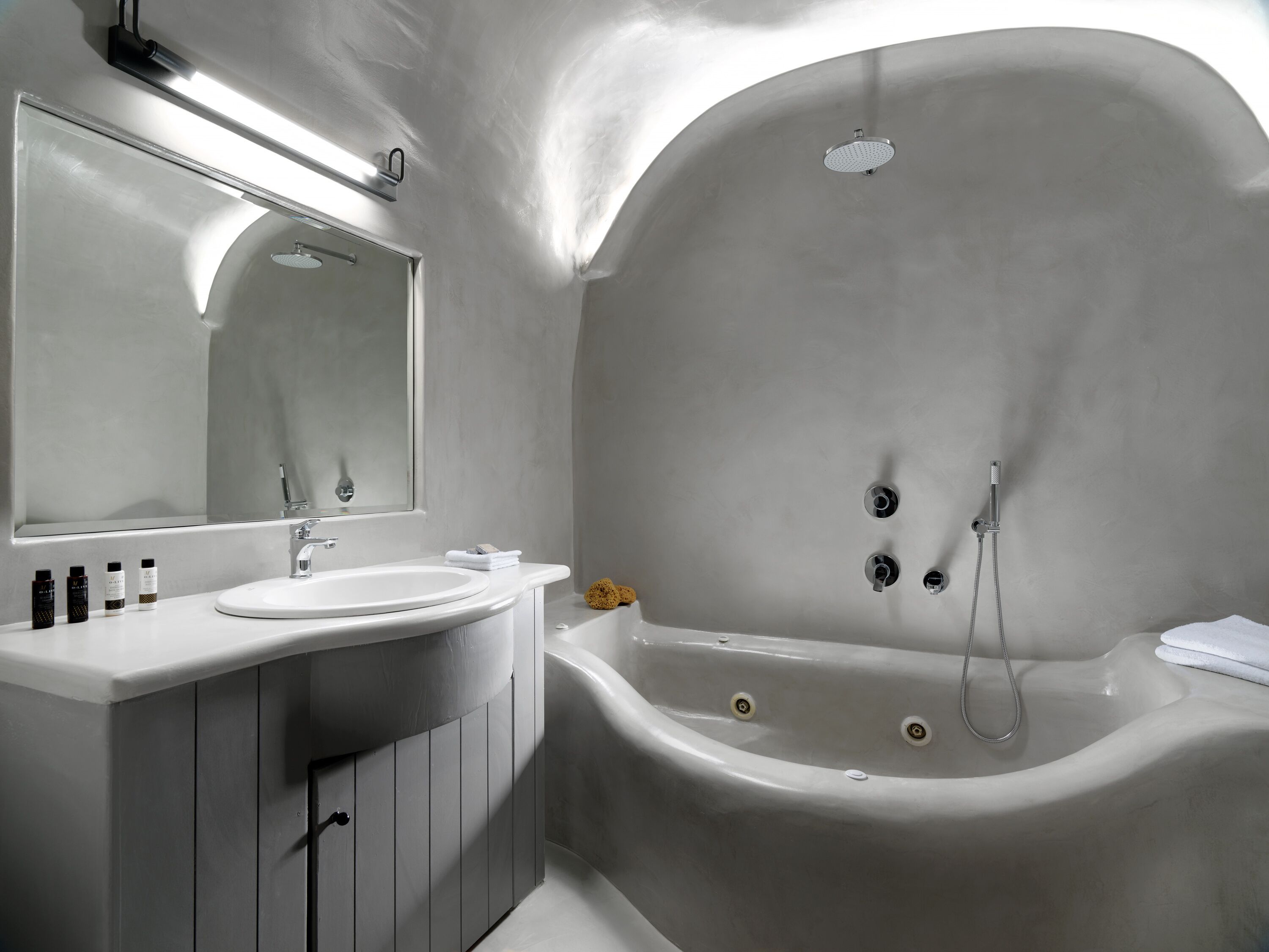 Et moderne badeværelse med et fritstående badekar, et stort spejl og en vaskepult med vask og toiletartikler.
