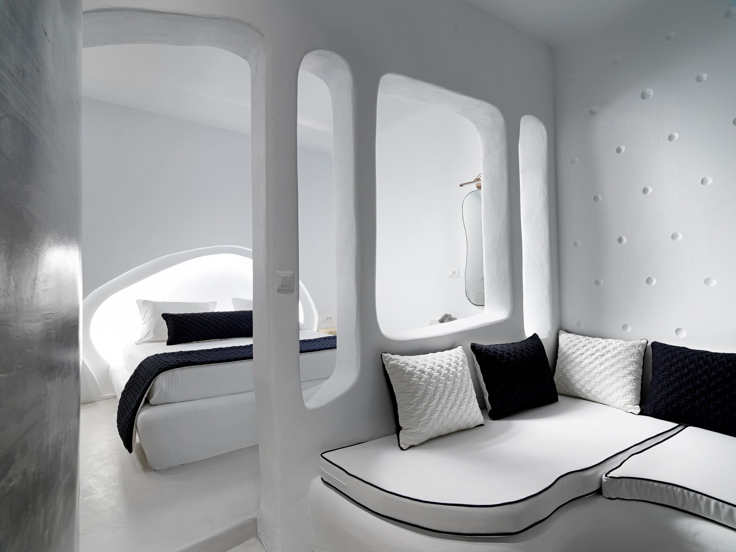 Ein modernes, minimalistisches Schlafzimmer mit einem gebogenen Bett, weißen Wänden und einem großen Fenster.