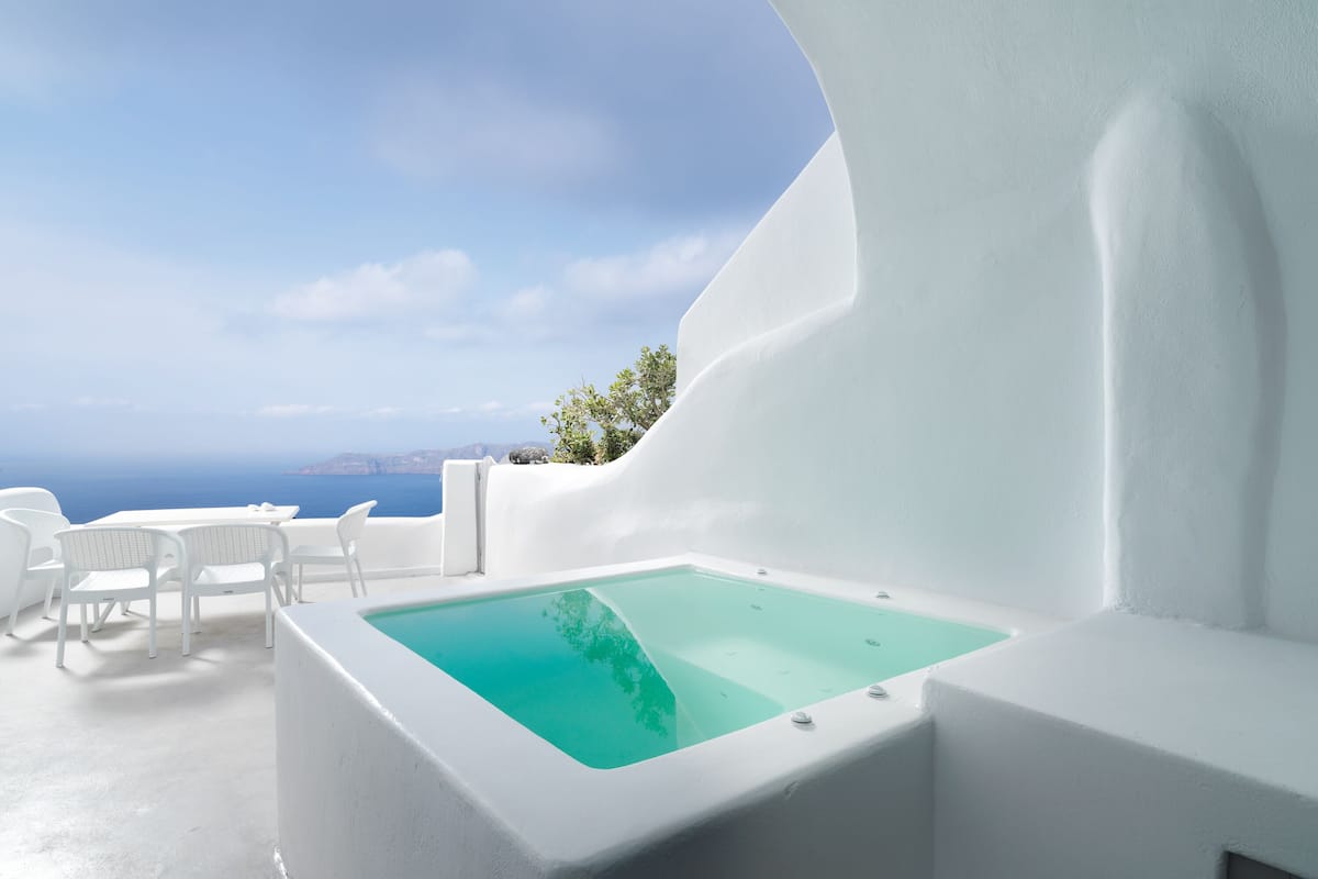 A white infinity pool with a clear blue view of the sea and distant land.