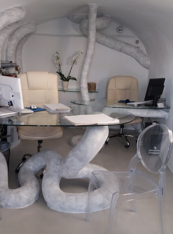 Un bureau moderne avec des tables en verre, des chaises en plastique transparent et un design de plafond original.
