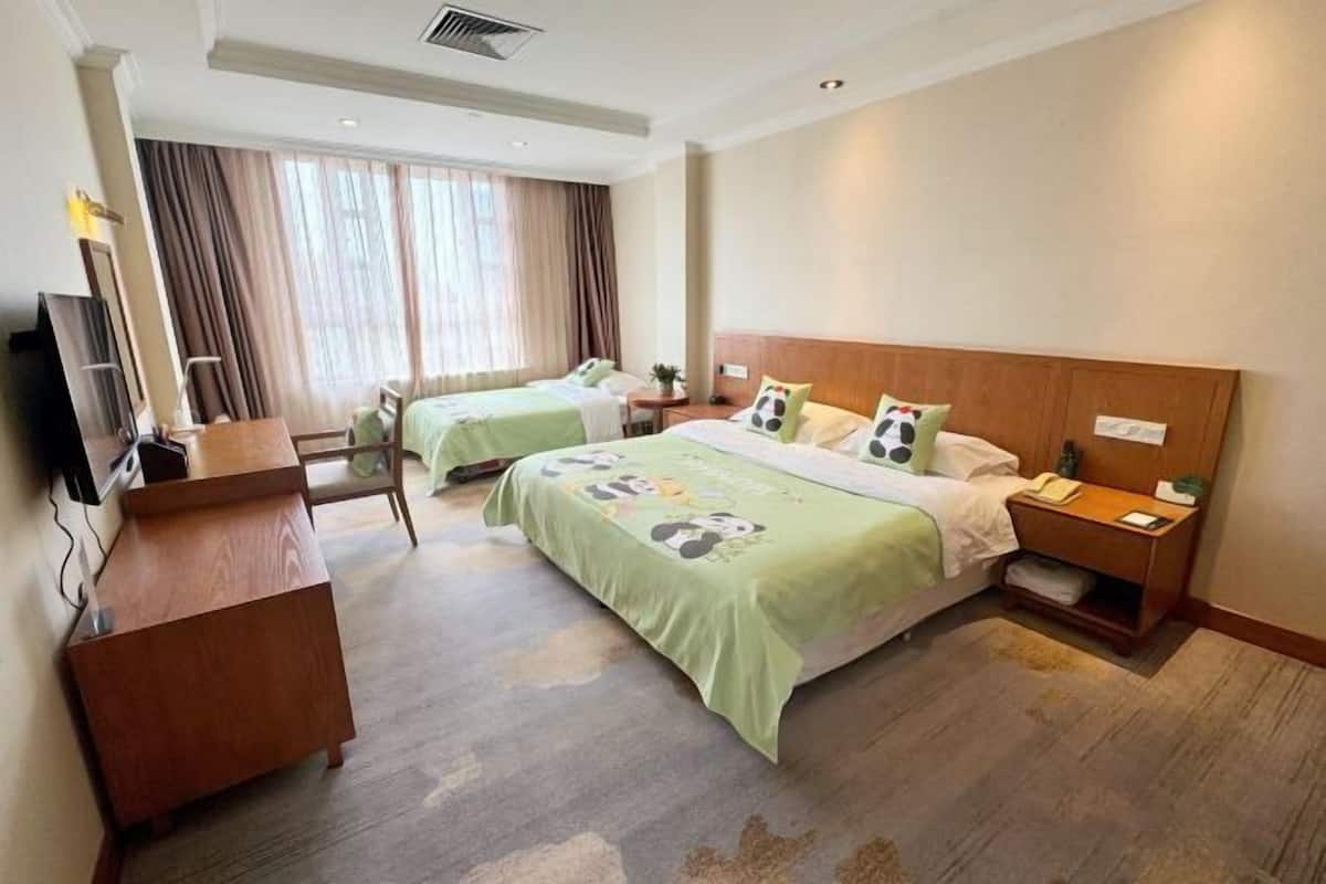 A hotel room with two beds, a desk, a TV, and a window with curtains.