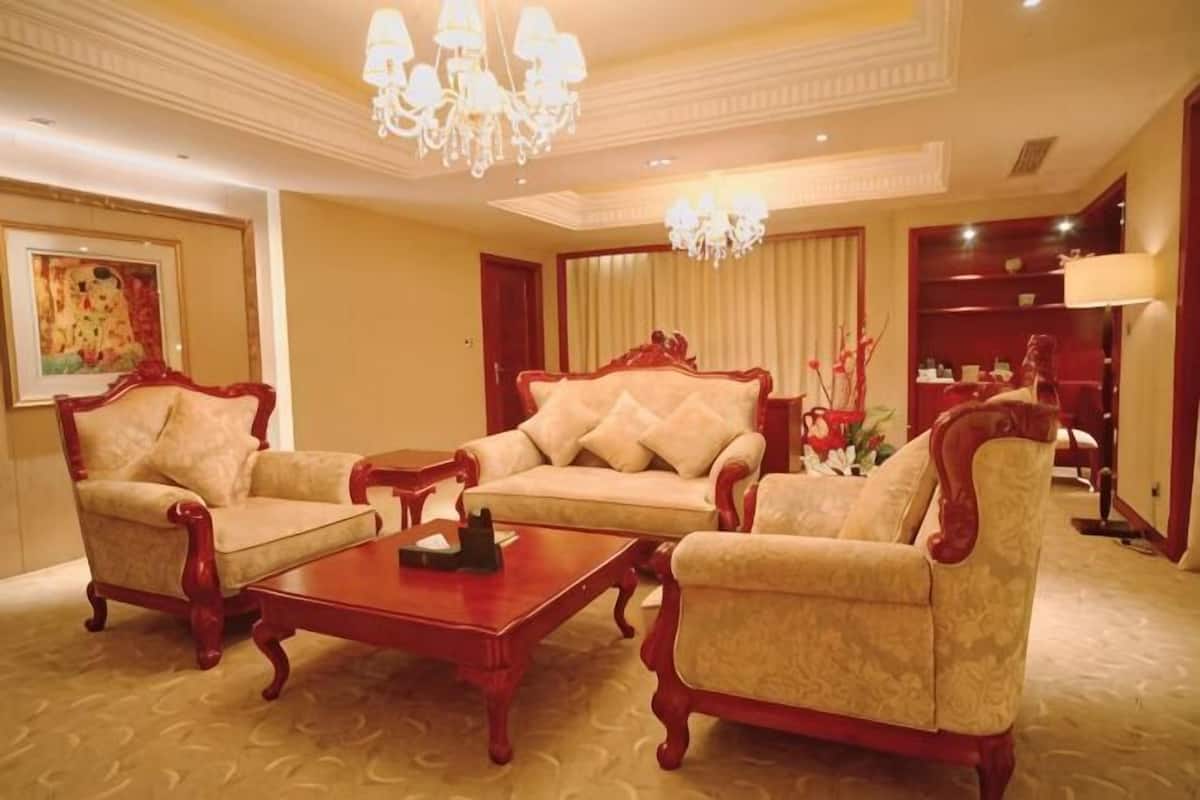 A hotel room with a sofa set, a coffee table, a chandelier, and a bookshelf.