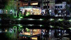 A modern building with a reflective pool, illuminated by ambient lighting. - Tieshan Hotel (Wuhu)