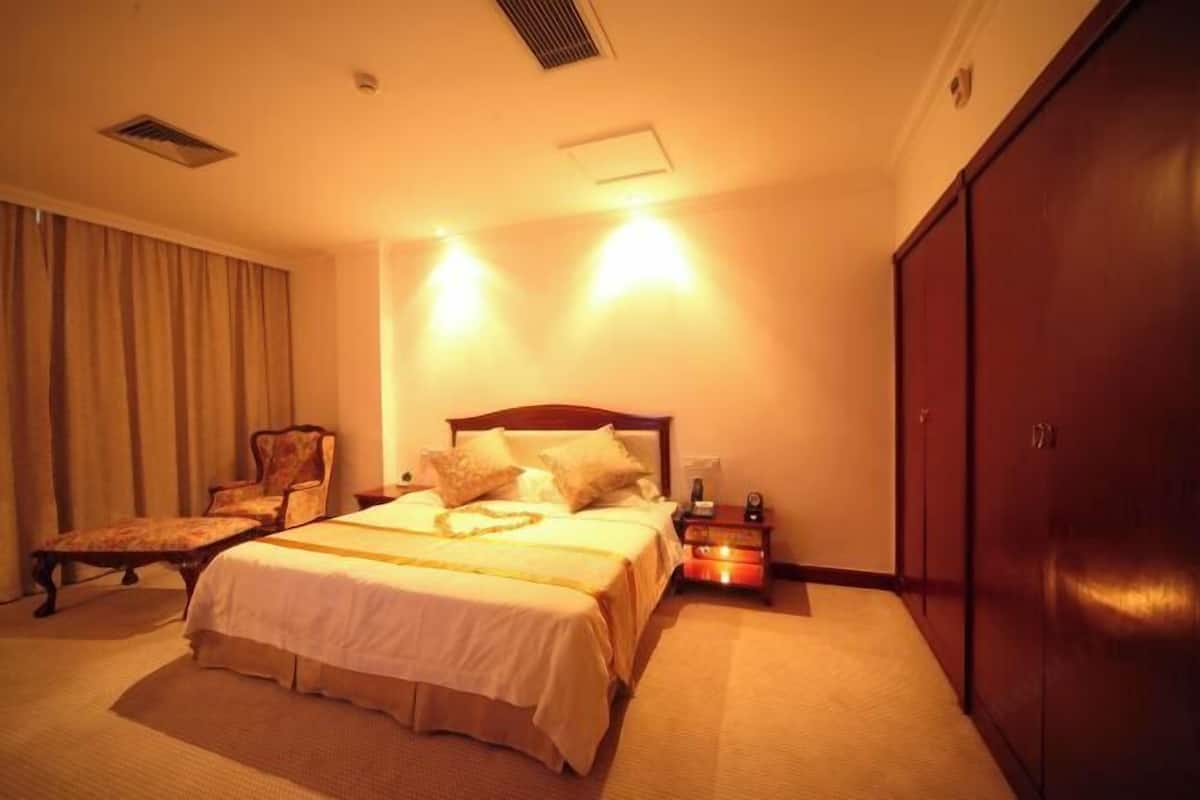 A hotel room with a large bed, a chair, a nightstand, and a wardrobe.