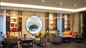 A modern hotel lobby with a circular wall decoration, comfortable seating, and a reception desk. - Tieshan Hotel (Wuhu)