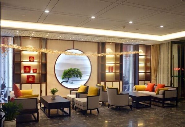 A modern hotel lobby with a circular wall decoration, comfortable seating, and a reception desk. - Tieshan Hotel (Wuhu)