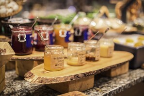 Une planche de service en bois, sur laquelle sont disposés des pots de miel étiquetés « Miel sauvage », est posée sur un plan de travail de cuisine.
