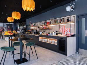 A modern bar area with a counter, stools, and a variety of food and drink items. - ibis Malaga Centro Ciudad (Málaga)