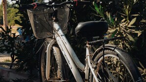 Een fiets geparkeerd op een onverhard pad, met een mandje aan de voorkant.