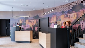 Een modern ingerichte receptie met een groot scherm, een receptiebalie en een trap.