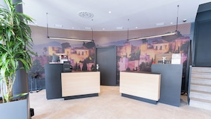 Een modern ingerichte receptie met twee balies, een groot digitaal scherm aan de muur en een potplant.