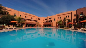 A pool area with lounge chairs and umbrellas, surrounded by buildings with a consistent architectural style. - ibis Marrakech Palmeraie Hotel (Marrakech)