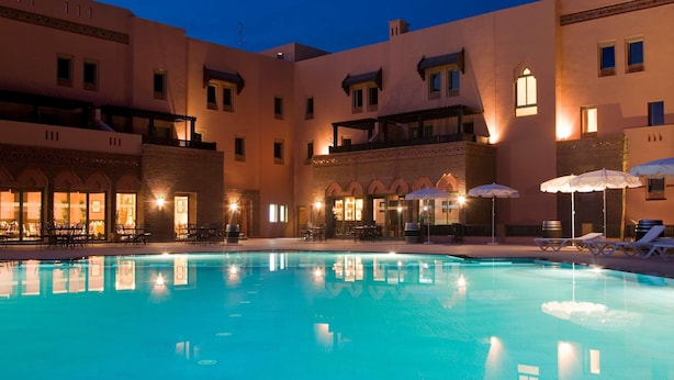 Un hotel con piscina, mobiliario exterior y un patio.