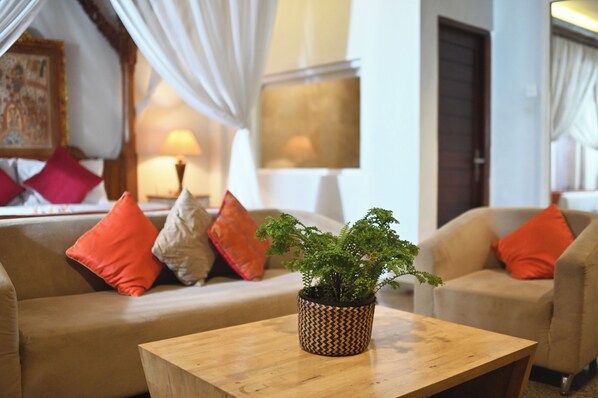 Uma sala de estar aconchegante com um sofá, poltronas, uma mesa de centro de madeira e um vaso com planta.