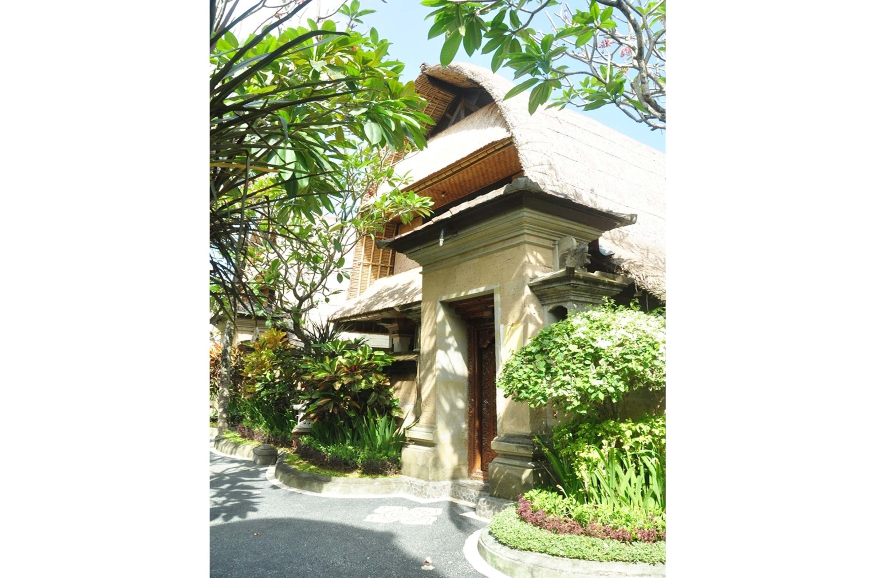 A traditional building with a thatched roof, surrounded by lush greenery and a well-maintained garden.
