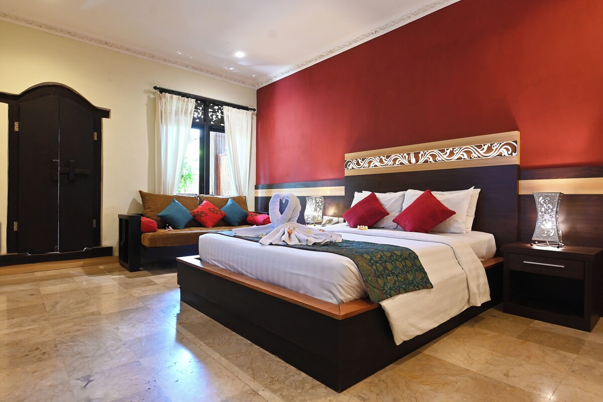 A hotel room with a large bed, a nightstand, a dresser, and a window with curtains.