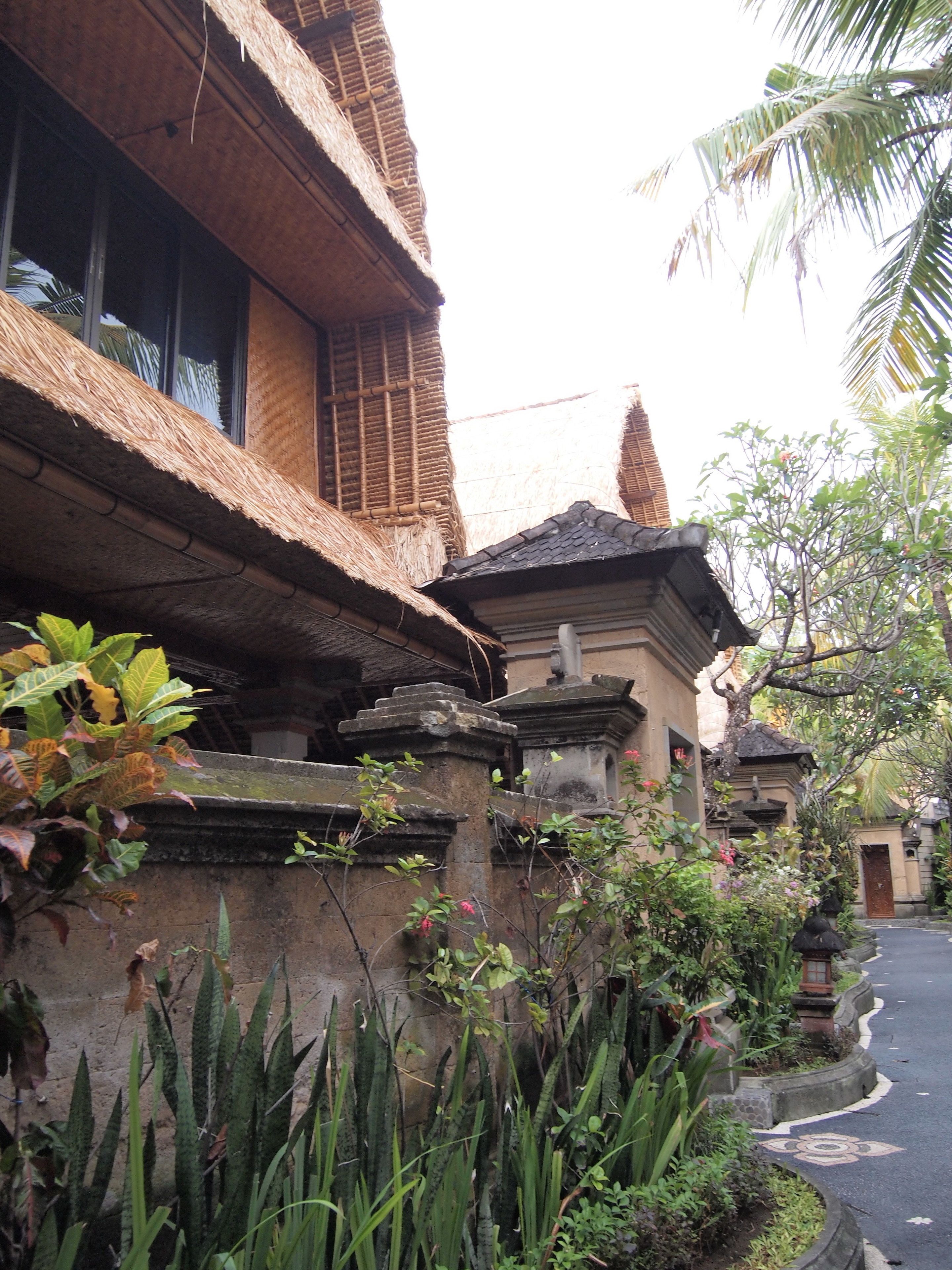 A traditional building with a thatched roof, stone pillars, and a small shrine.