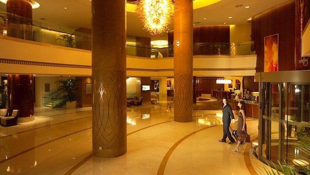 A spacious lobby with a central column, a chandelier, and a reception desk. - Songjiang New Century Grand Hotel Shanghai (Shanghai)