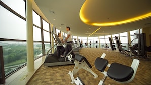 A gym with cardio equipment, weight machines, and a view of the city. - Songjiang New Century Grand Hotel Shanghai (Shanghai)