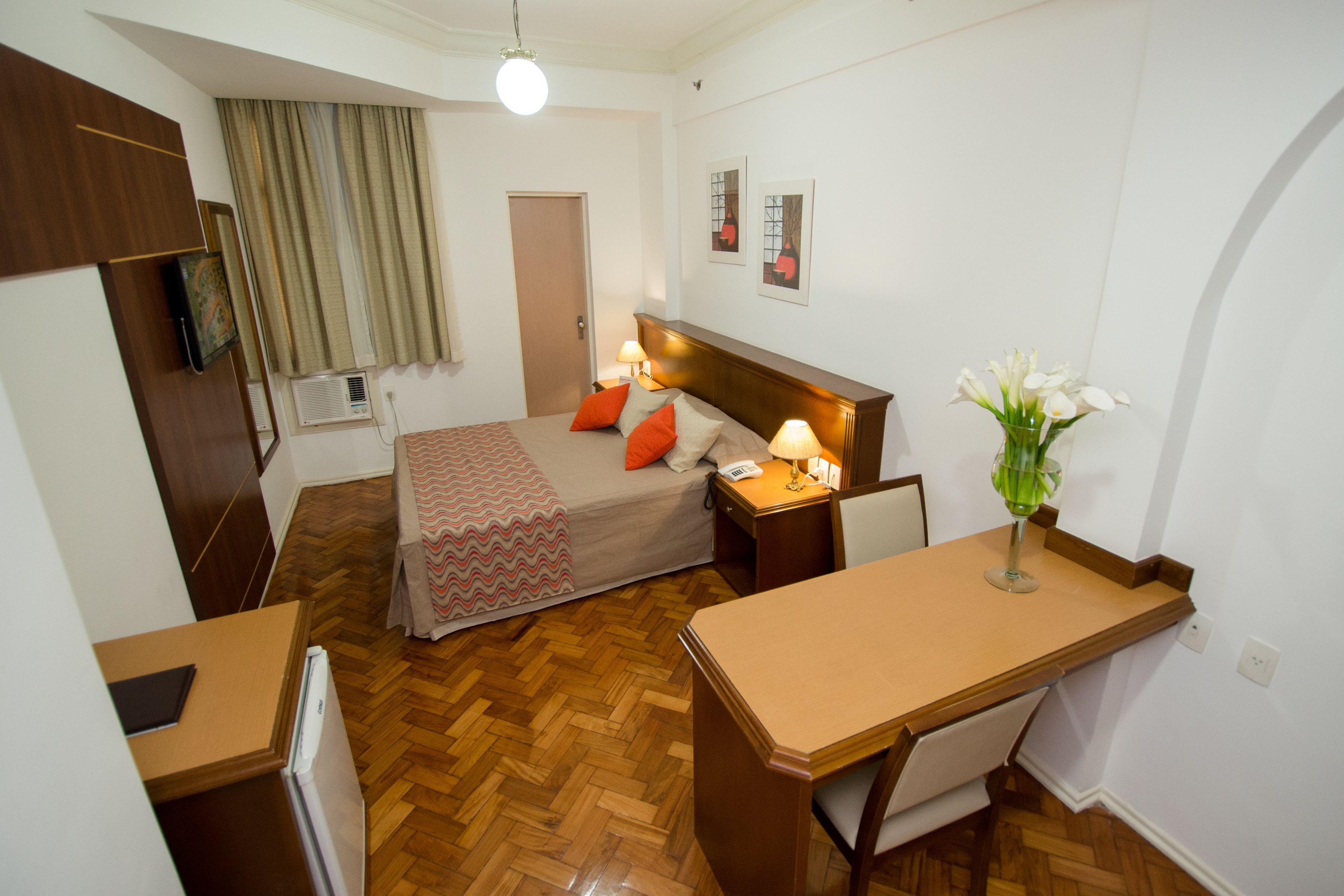 Une chambre d’hôtel comprenant un lit, une table de chevet, un bureau et une petite kitchenette.