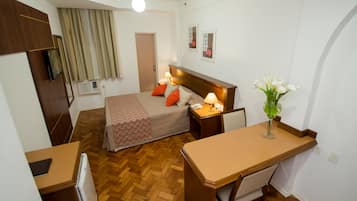Une chambre d’hôtel comprenant un lit, une table de chevet, un bureau et une petite kitchenette.