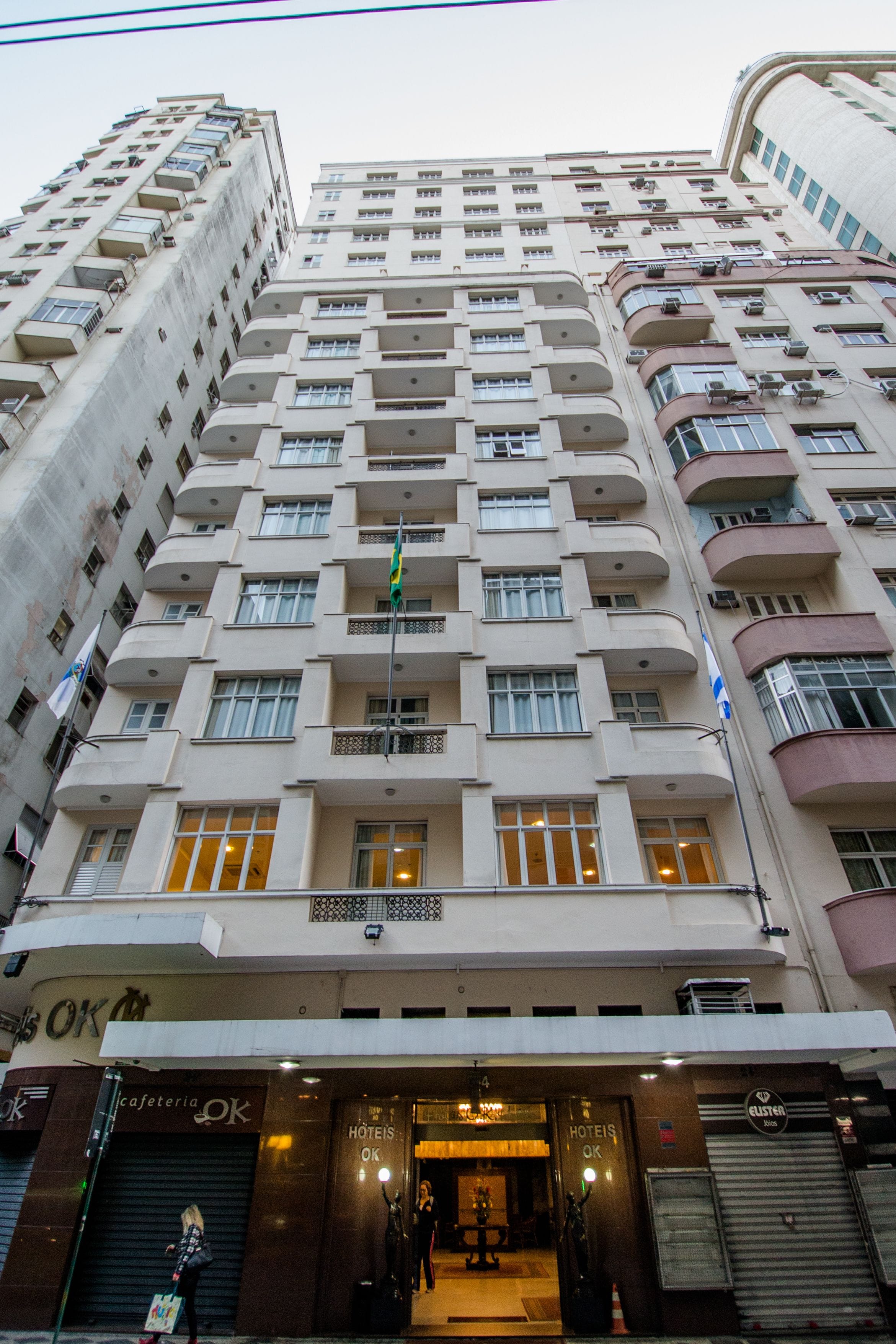 A multi-story hotel with balconies, a visible flag, and a sign indicating it is a hotel.