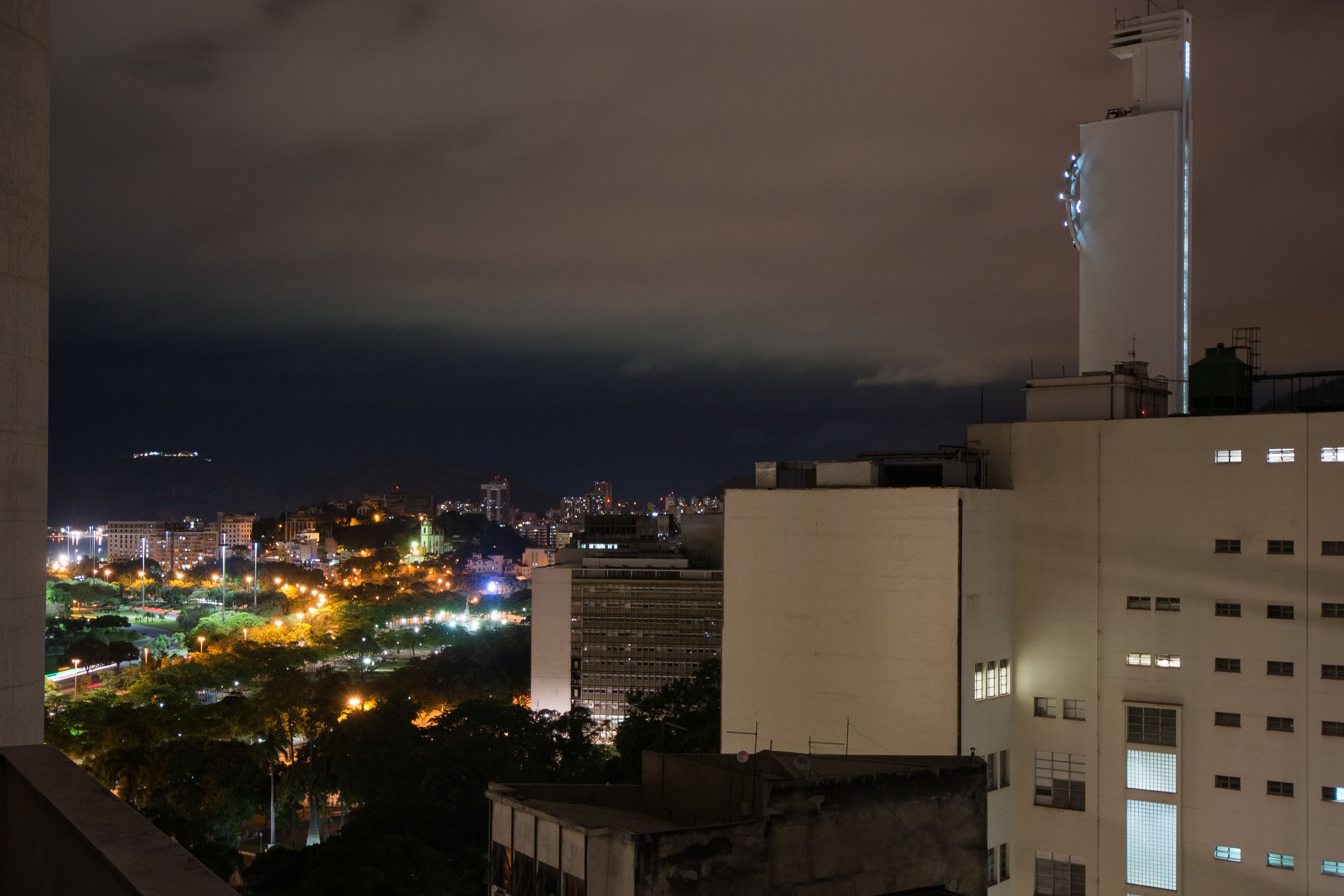 Un paisaje urbano nocturno con edificios iluminados y una zona de parque.