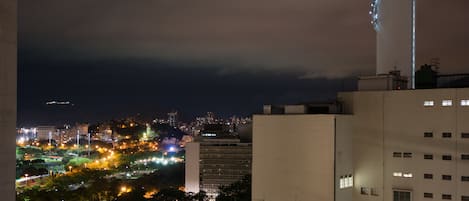 Un paisaje urbano nocturno con edificios iluminados y una zona de parque.