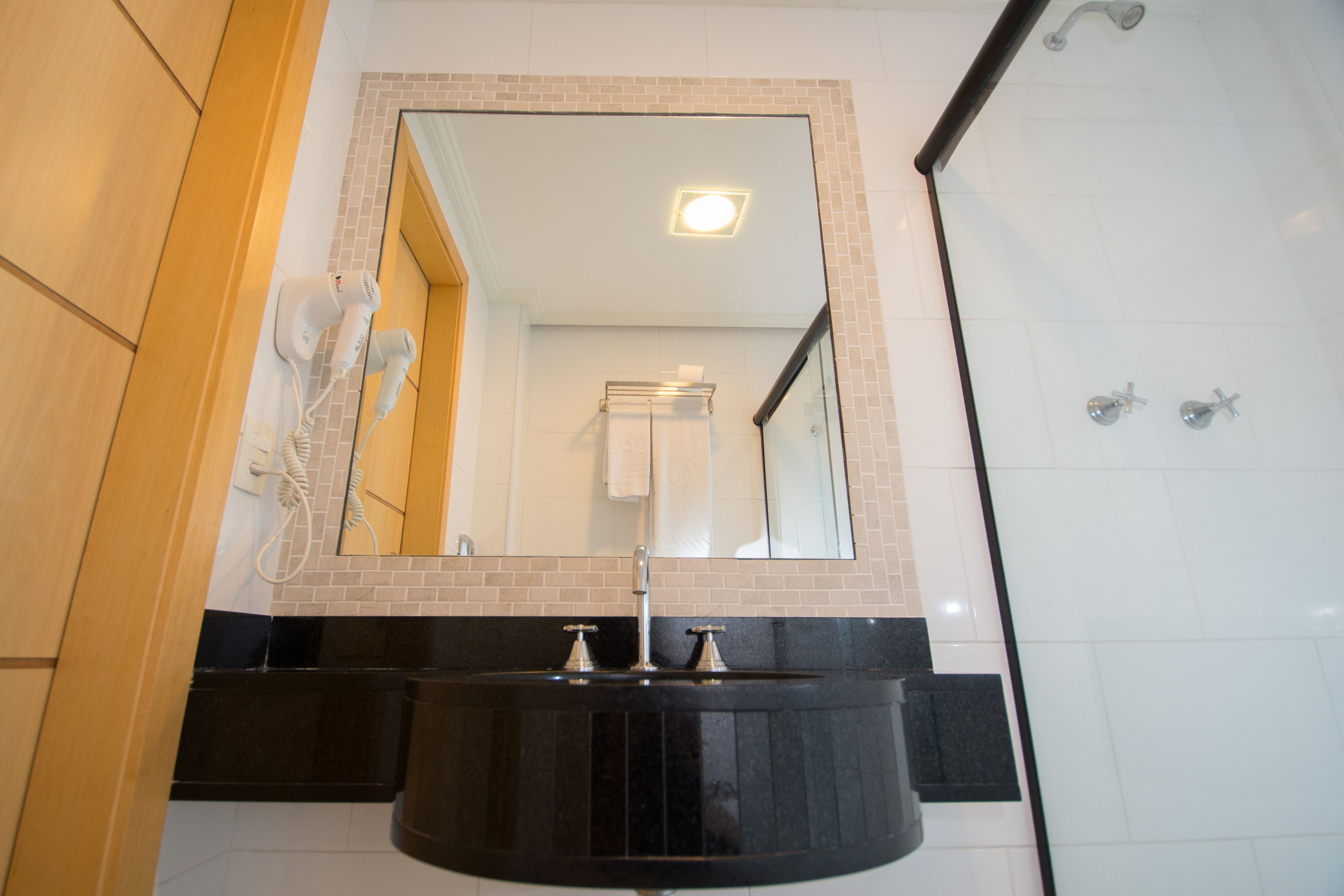 Un baño con lavamanos negro, espejo y ducha.