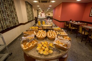 Buffet com diversos pães e bebidas.