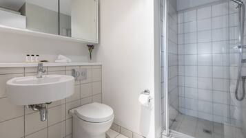 A modern bathroom with a white sink, toilet, and glass-enclosed shower.