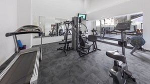 A gym with cardio equipment, weight machines, and a mirrored wall. - Auckland Harbour Suites (Auckland)