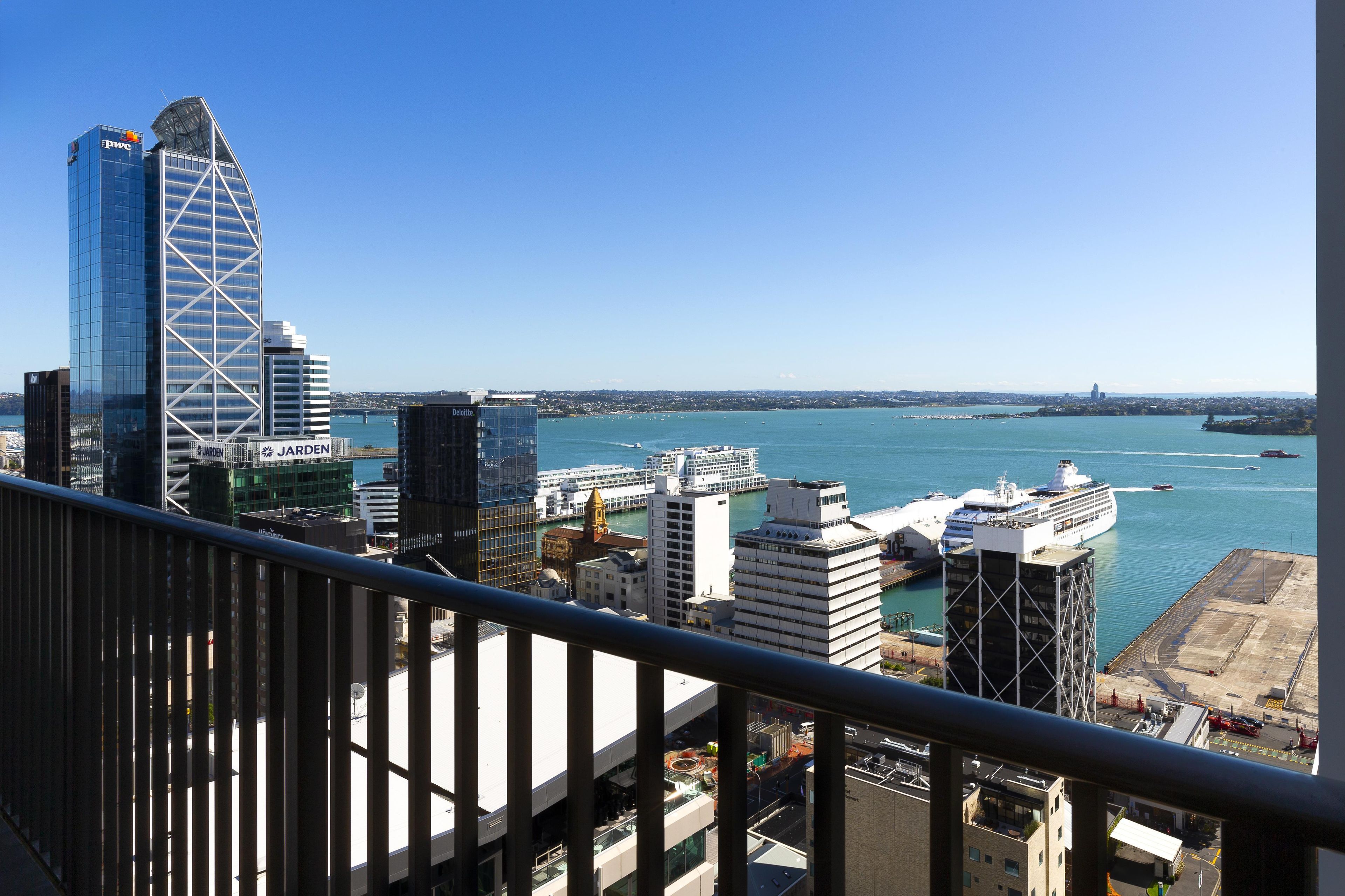 A cityscape with modern buildings, a waterfront, and a clear sky.