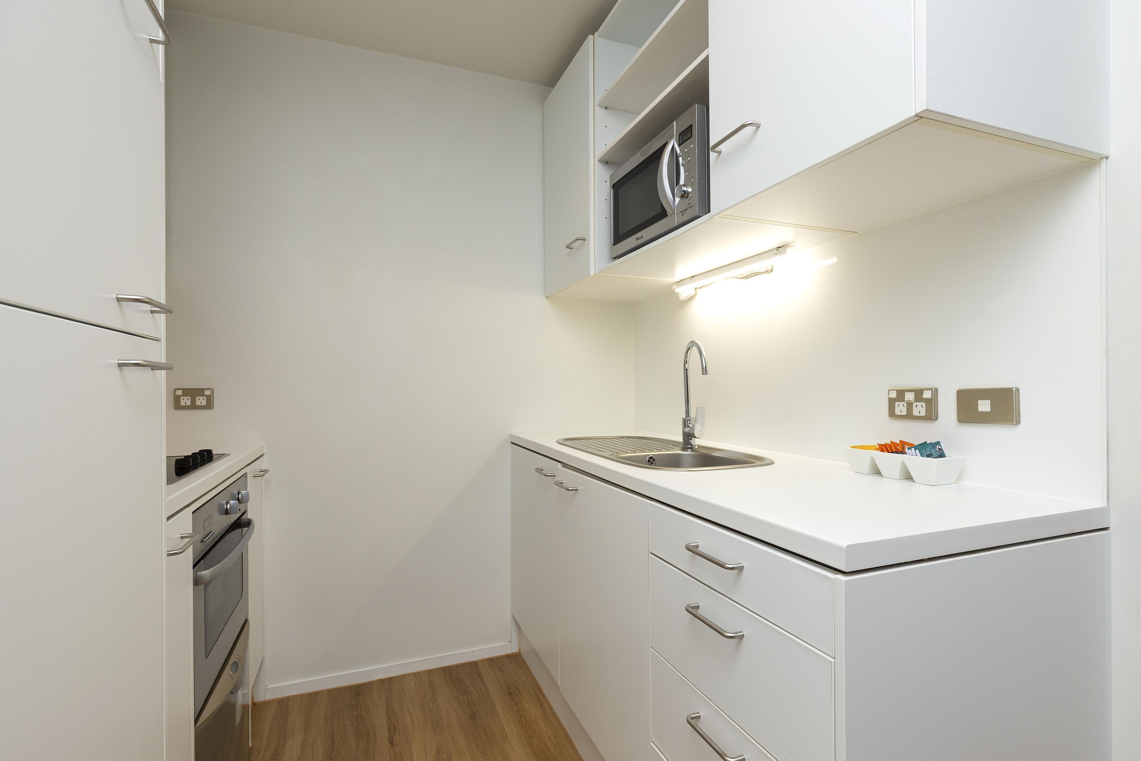 A compact kitchen with a microwave, stove, and sink.
