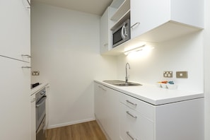 A compact kitchen with a microwave, stove, and sink.