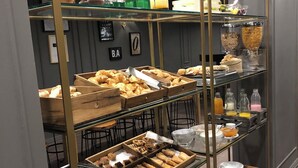 Een ontbijtbuffet met diverse gebakjes, brood en drankjes.