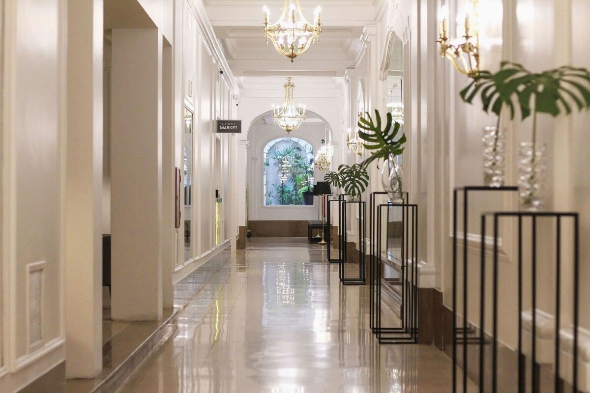 Una hall d'albergo con pavimento lucido, un lampadario e piante in vaso.