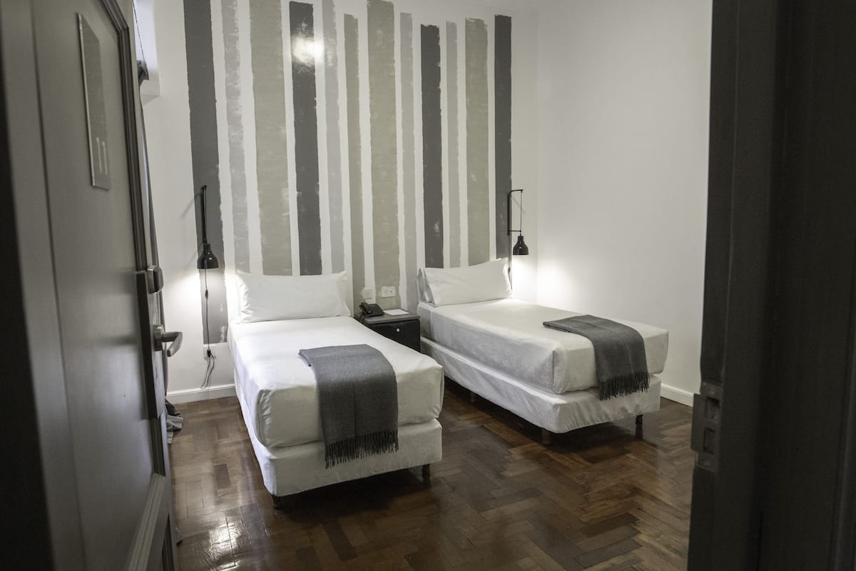 Een kamer met twee bedden, een houten vloer, een gestreepte wand en een deur.