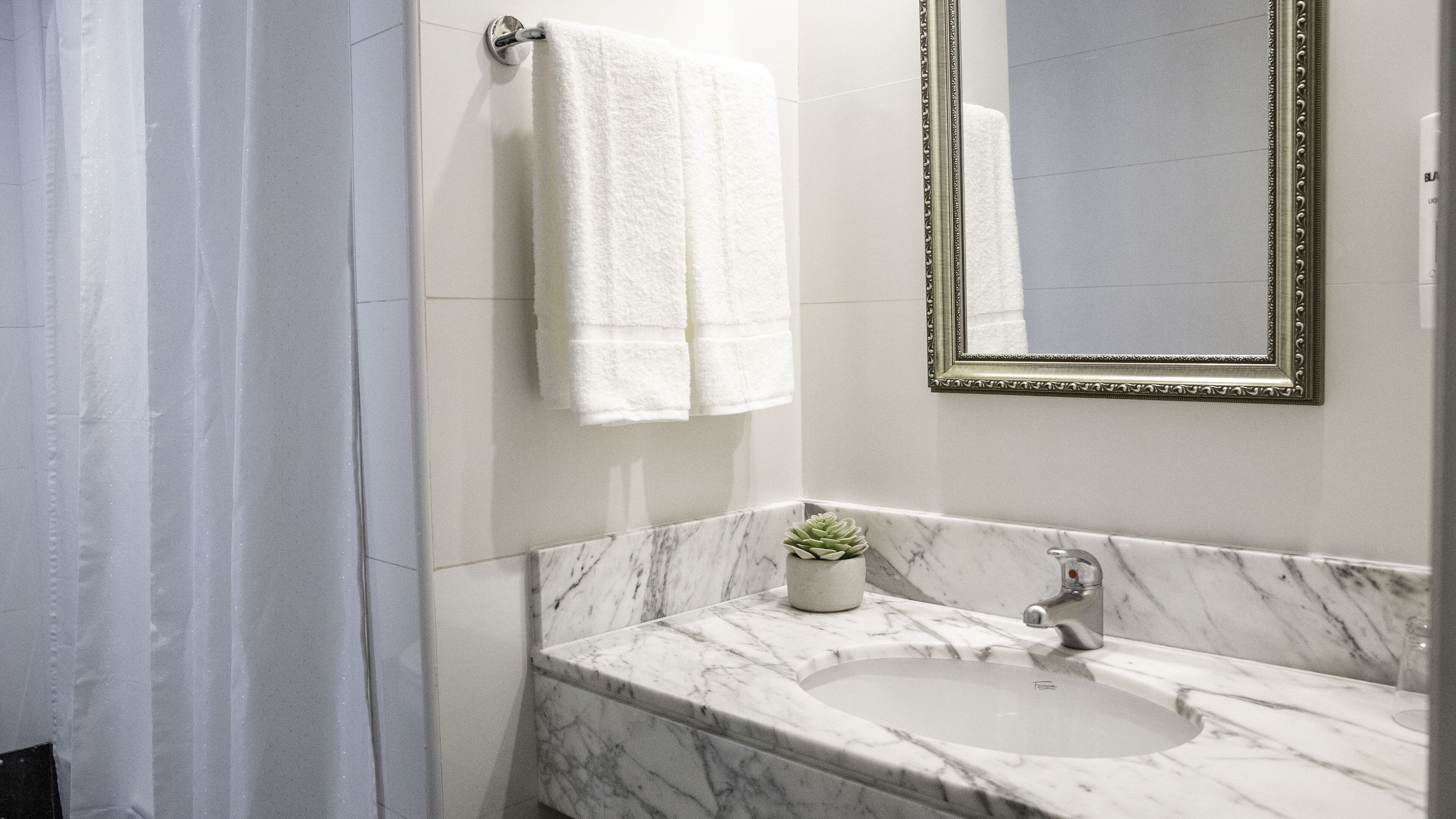 A bathroom with a marble sink, a mirror with an ornate frame, and a towel hanging on a rack.