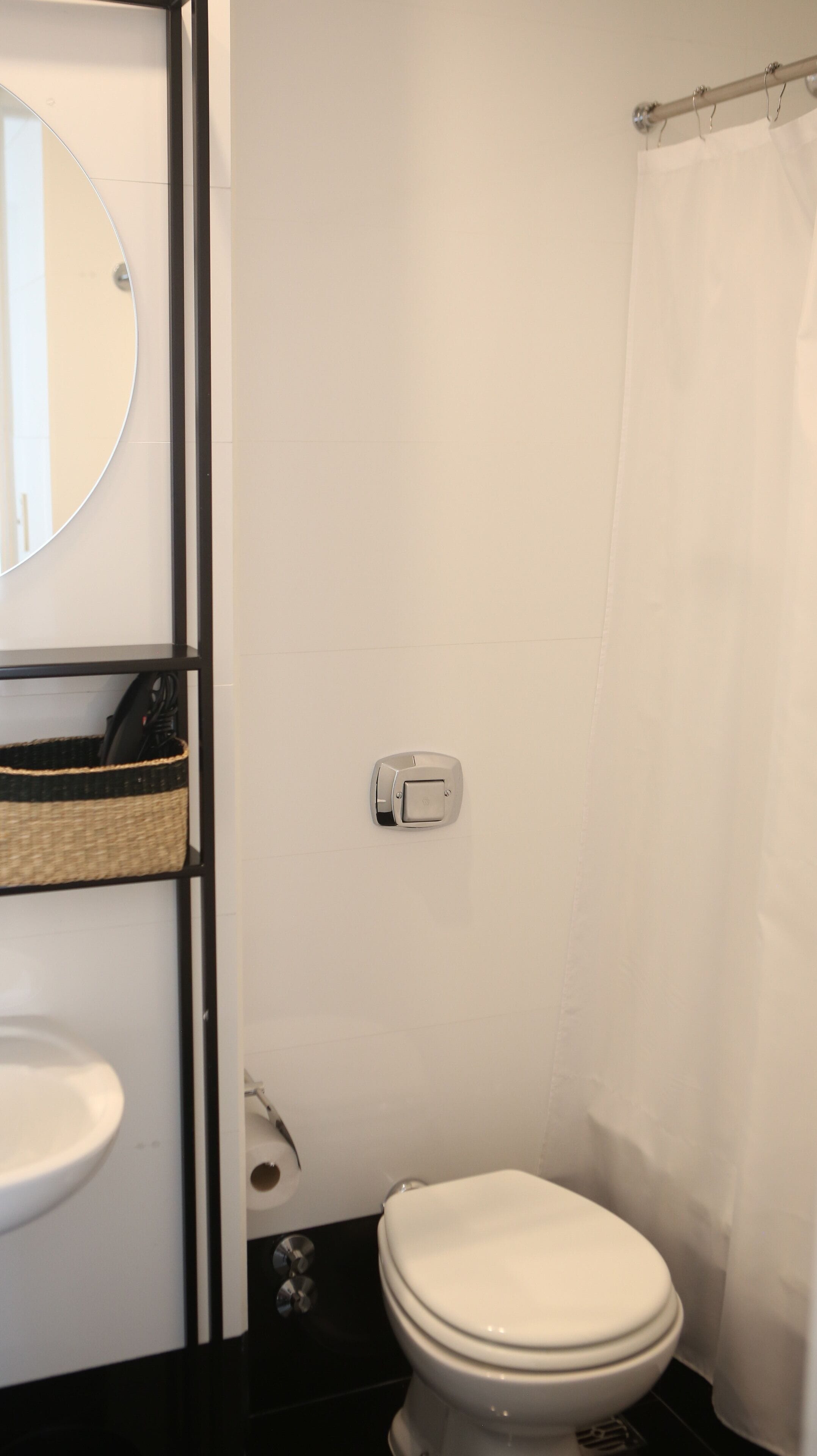 A bathroom with a toilet, a sink, a mirror, and a shower curtain.