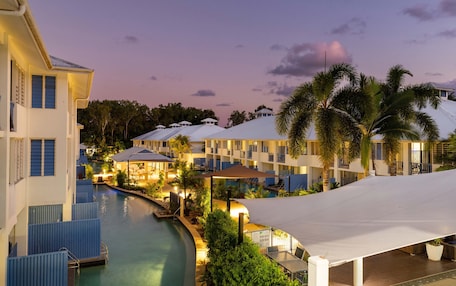 A resort with a swimming pool, multiple buildings, and palm trees.