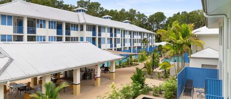 Un hotel con varios pisos, piscina al aire libre y zona de comedor.